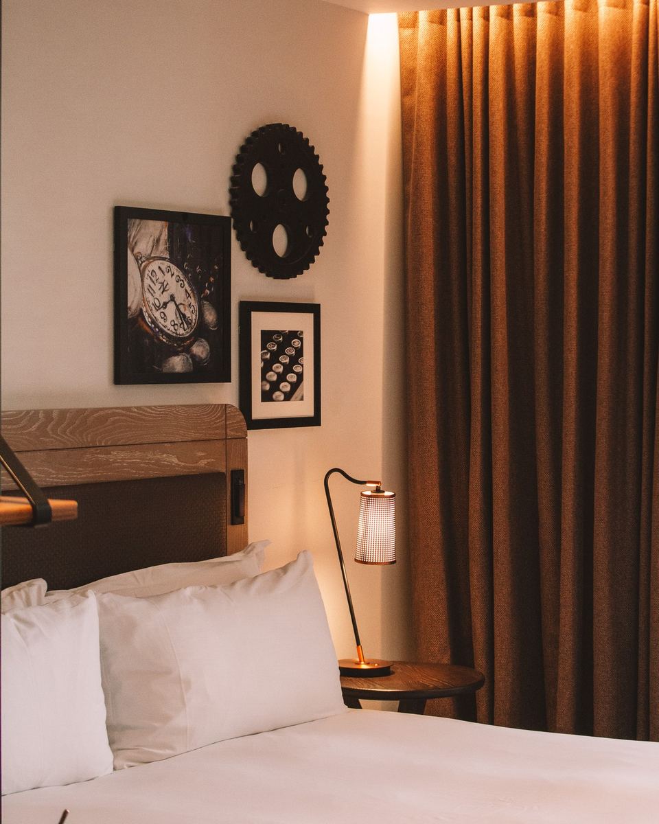 Hotel bed with warm lighting and framed art