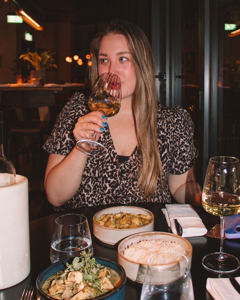 Elise sipping white wine at dinner