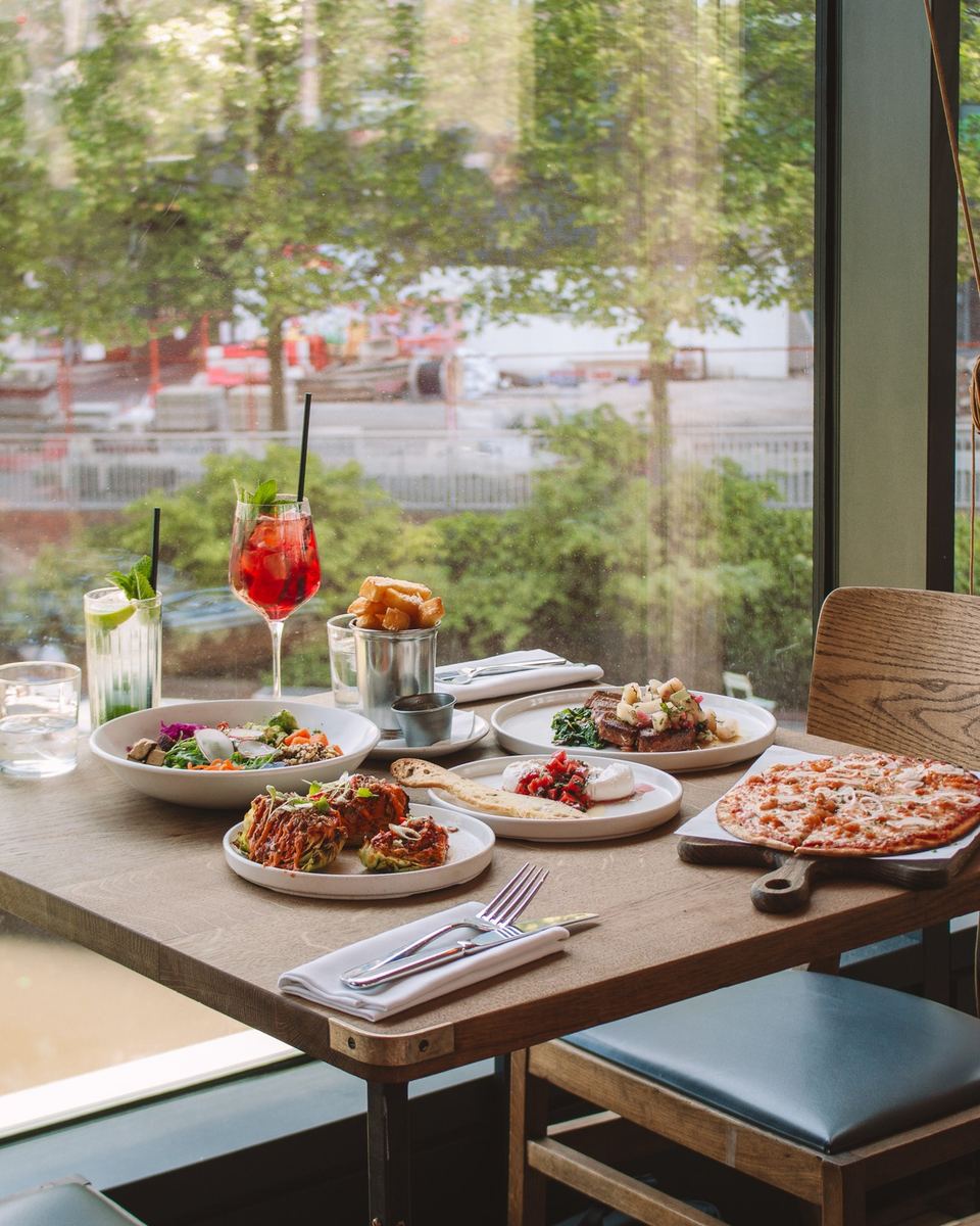 Spread of summer dishes and a spritz by a big window at The Lighterman