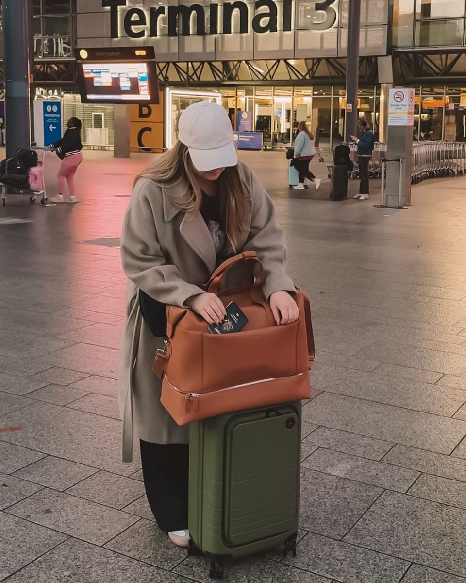 Elise at Terminal 3 with a green Monos suitcase and tan bag